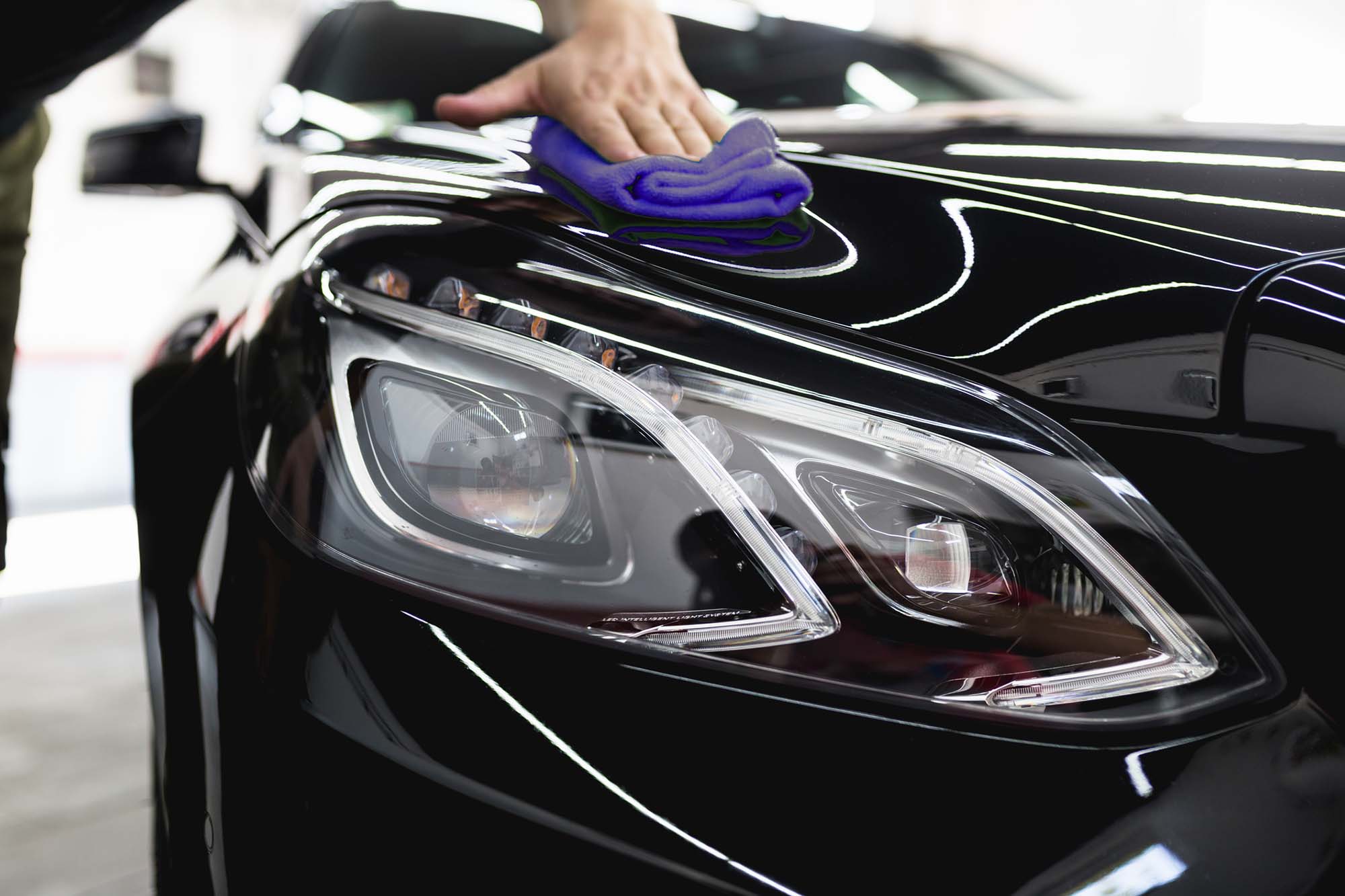 Car cleaning and polishing. A man cleaning car with microfiber cloth, car detailing or valeting concept.