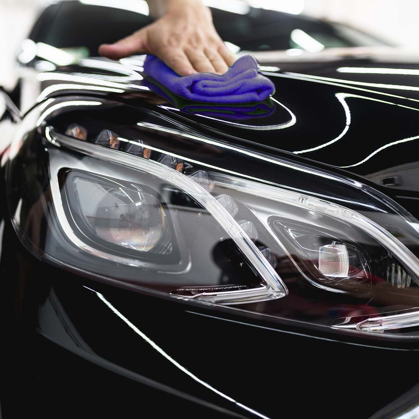 Car cleaning and polishing. A man cleaning car with microfiber cloth, car detailing or valeting concept.